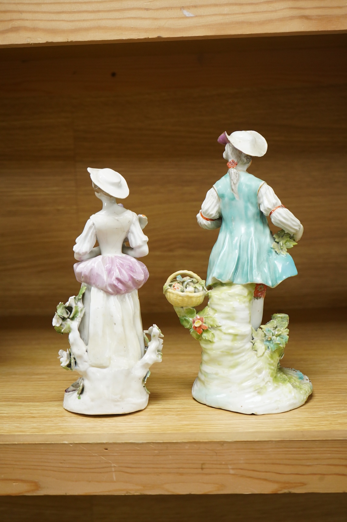 A Derby porcelain figure of a lady holding a bird, c.1760-65 and a Derby porcelain figure of a gentleman fruit seller, largest 24cm high (2)
